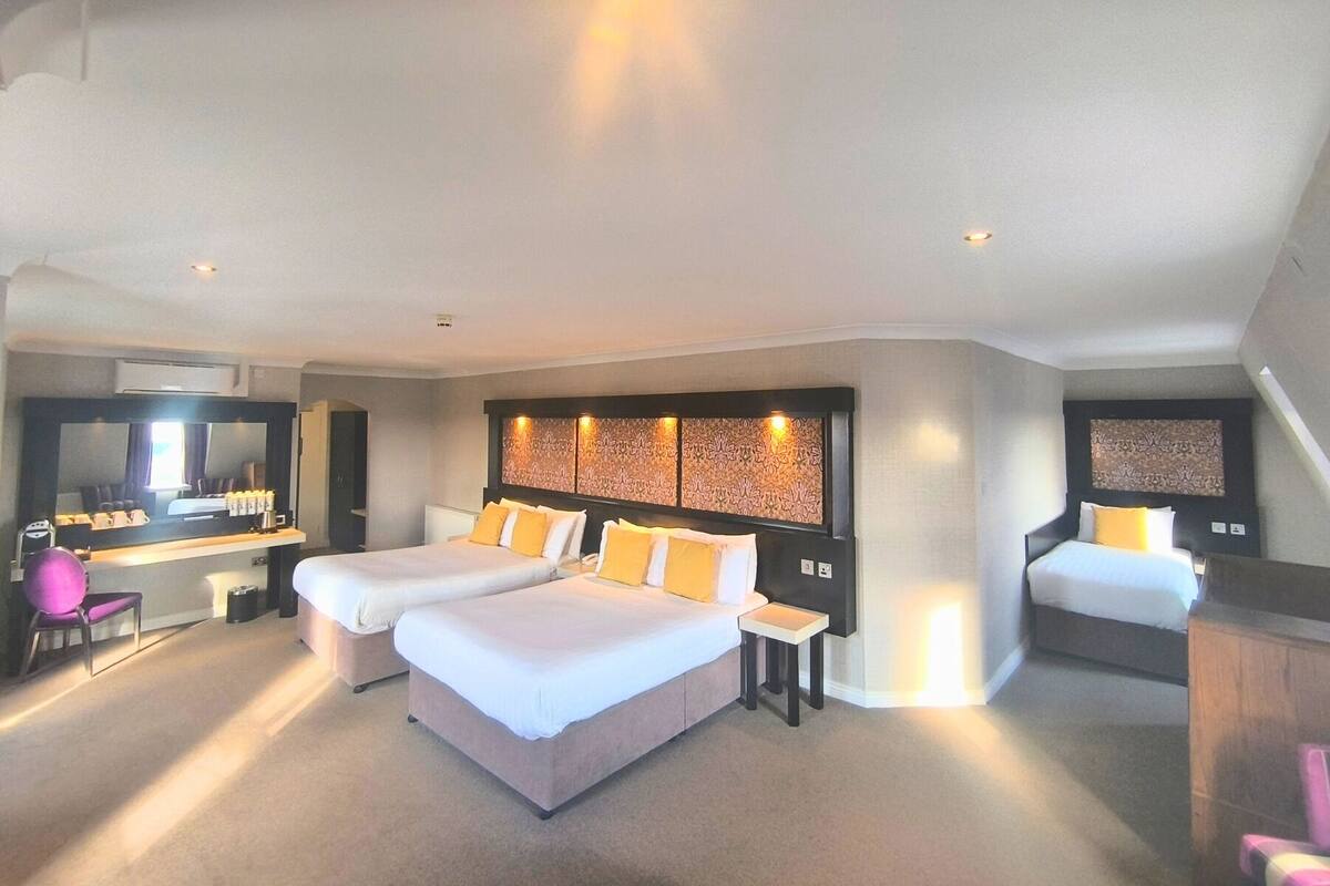 A hotel room with two beds, a desk, and a large mirror.