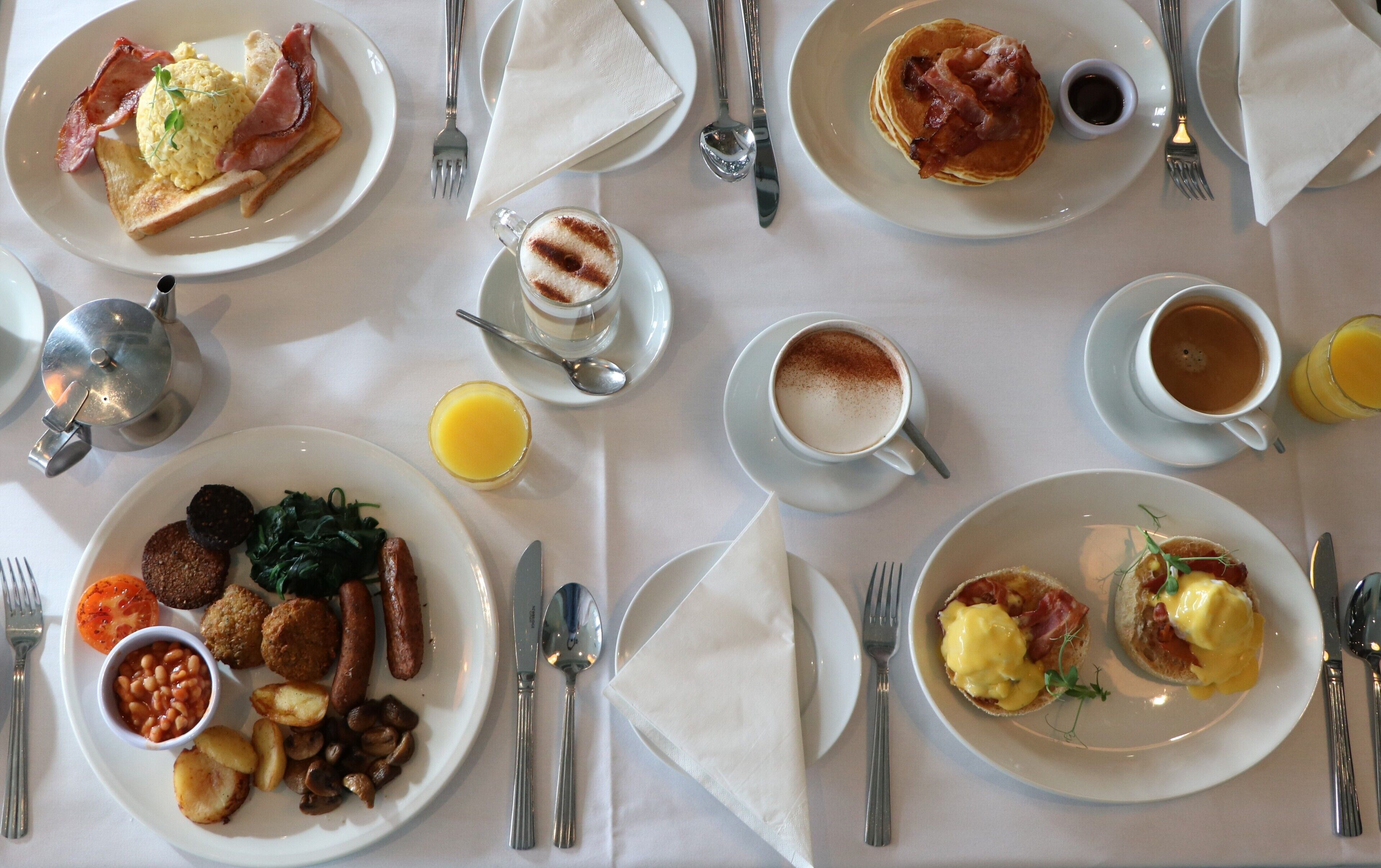 Un buffet de petit-déjeuner proposant divers plats, notamment des œufs, du bacon, des saucisses et des viennoiseries.