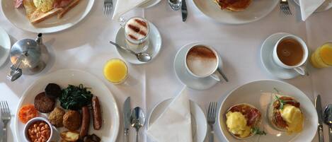 A breakfast buffet with various dishes, including eggs, bacon, sausages, and pastries.