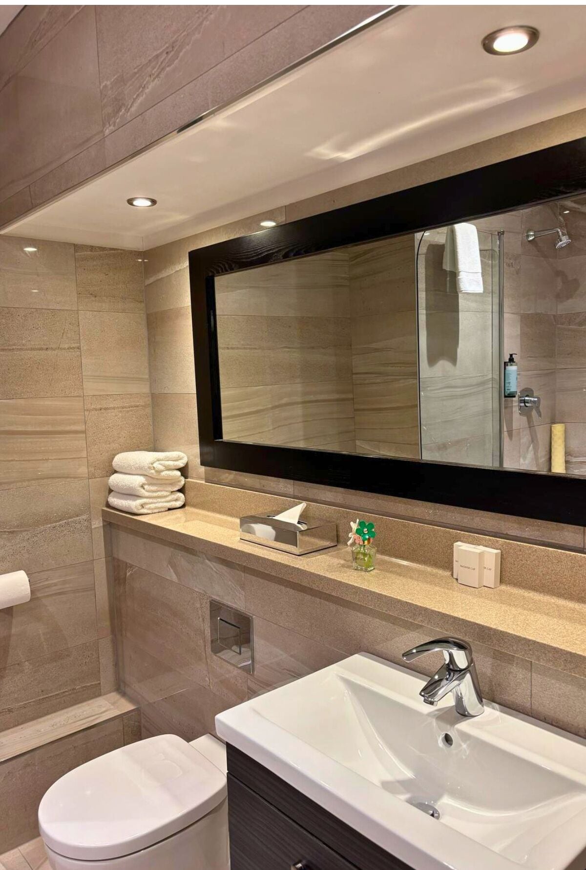 Egy modern fürőszoba, amelyben nagy tükör, mosdókagyló és WC található.