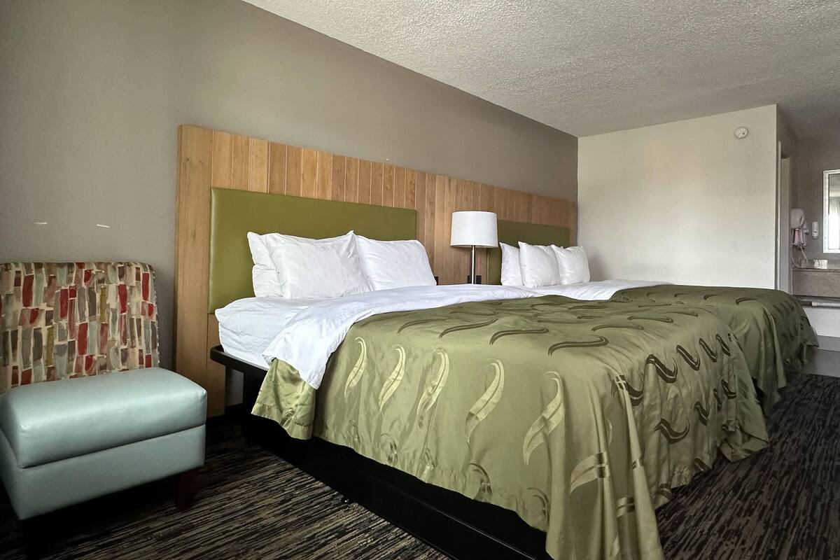 Habitación de hotel con cama, una zona de estar pequeña, una lámpara y un espejo.