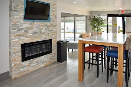 A modern interior with a stone fireplace, a flat-screen TV, and a bar area with stools.