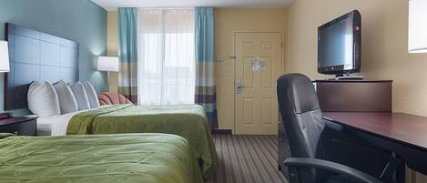 Une chambre d’hôtel avec deux lits, un bureau, une chaise, une télévision et une porte.
