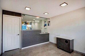 A reception area with a white door, a dark reception desk, a small cabinet, and a mirror reflecting the interior.