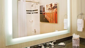 A hotel bathroom with a large mirror, a sink, and toiletries on the counter.