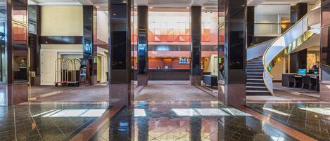 A spacious lobby with a central atrium, a staircase, and a reception desk.