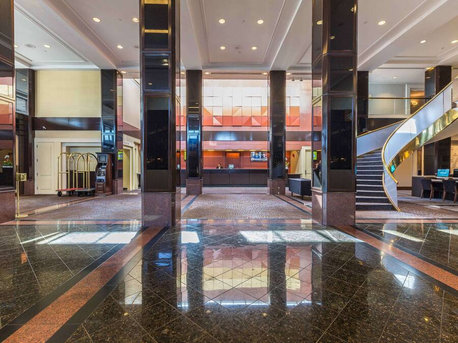 Un lobby amplio con un atrio central, una escalera y una recepción.