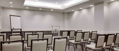 A conference room with rows of chairs, a podium, and a whiteboard.