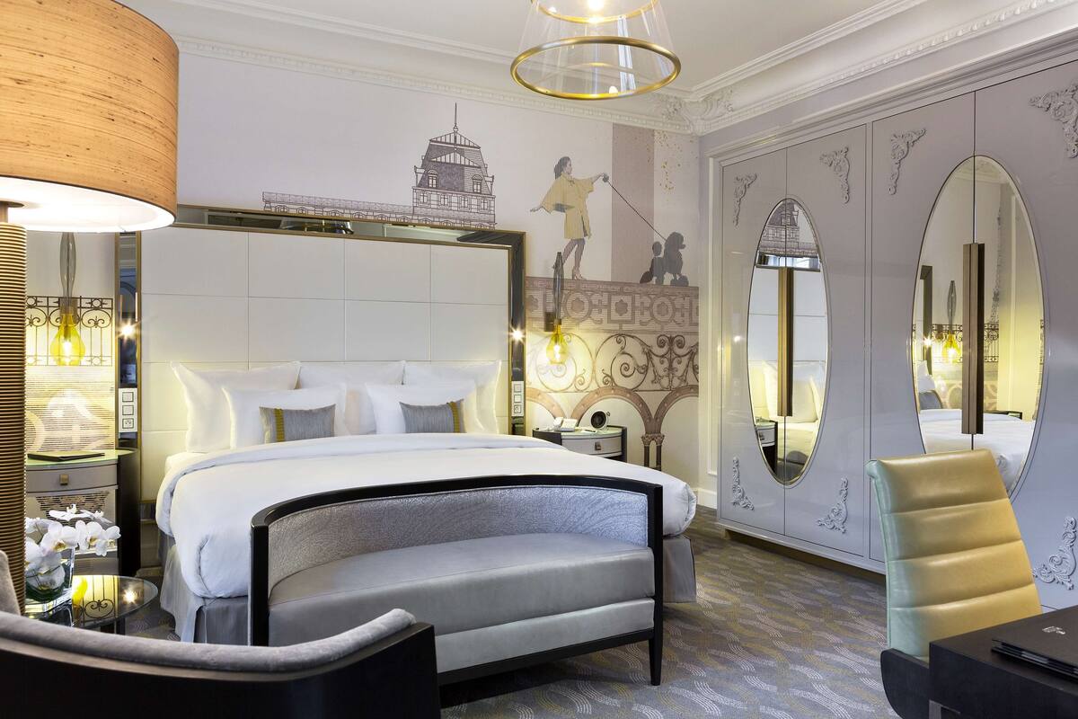 Una habitación de hotel moderna con una cama grande, una zona de estar y una mesa de comedor.