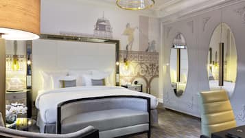 A modern hotel room with a large bed, a seating area, and a dining table.
