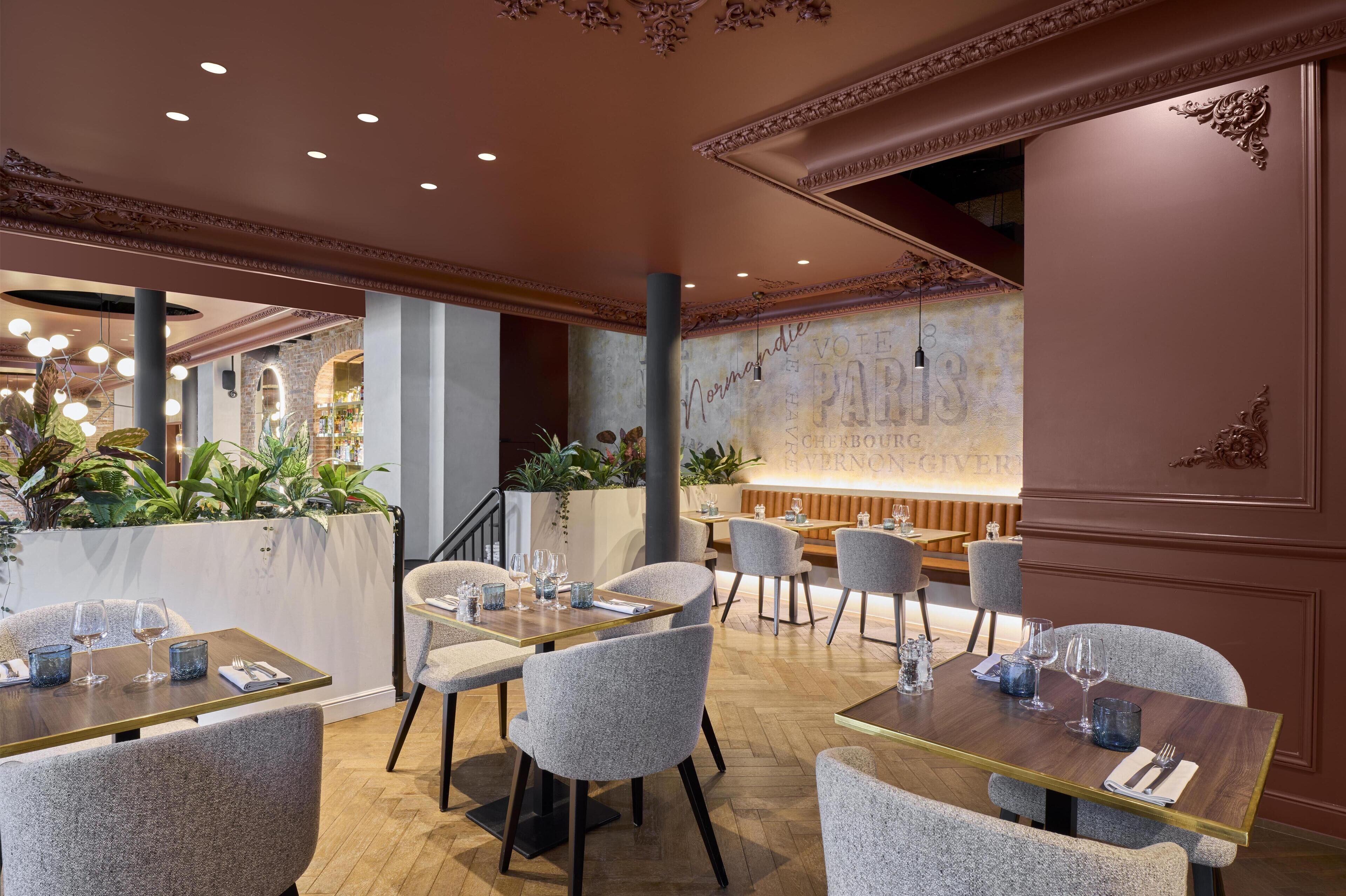 Un ristorante dall'arredamento classico, con un'area bar, diversi tavoli e una parete decorativa con scritte.