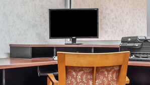 A workspace with a monitor, a printer, and a chair.