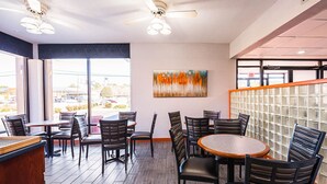 A restaurant with a modern interior, featuring a mix of round and rectangular tables, black chairs, and a ceiling fan. - Quality Inn Dillon (Dillon)