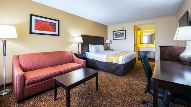 A hotel room with a bed, a sofa, a desk, and a chair. - Quality Inn Dillon (Dillon)