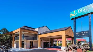 Welcome to Quality Inn, a two-story hotel with a flat roof and landscaped surroundings.