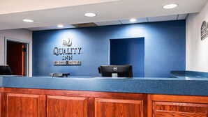A hotel reception desk with a blue wall, a wooden counter, and a Dell computer. - Quality Inn Dillon (Dillon)