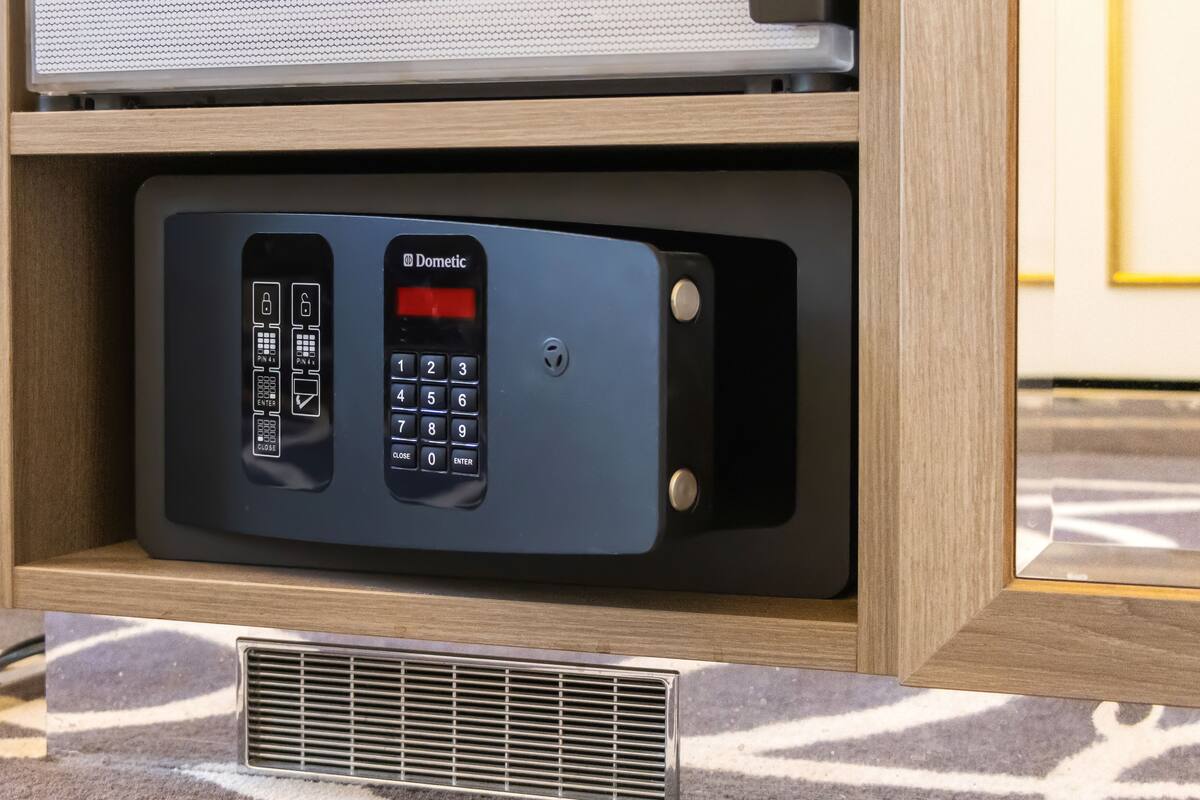 A security keypad with a numeric keypad and a red display, housed in a wooden cabinet with a vent below it.