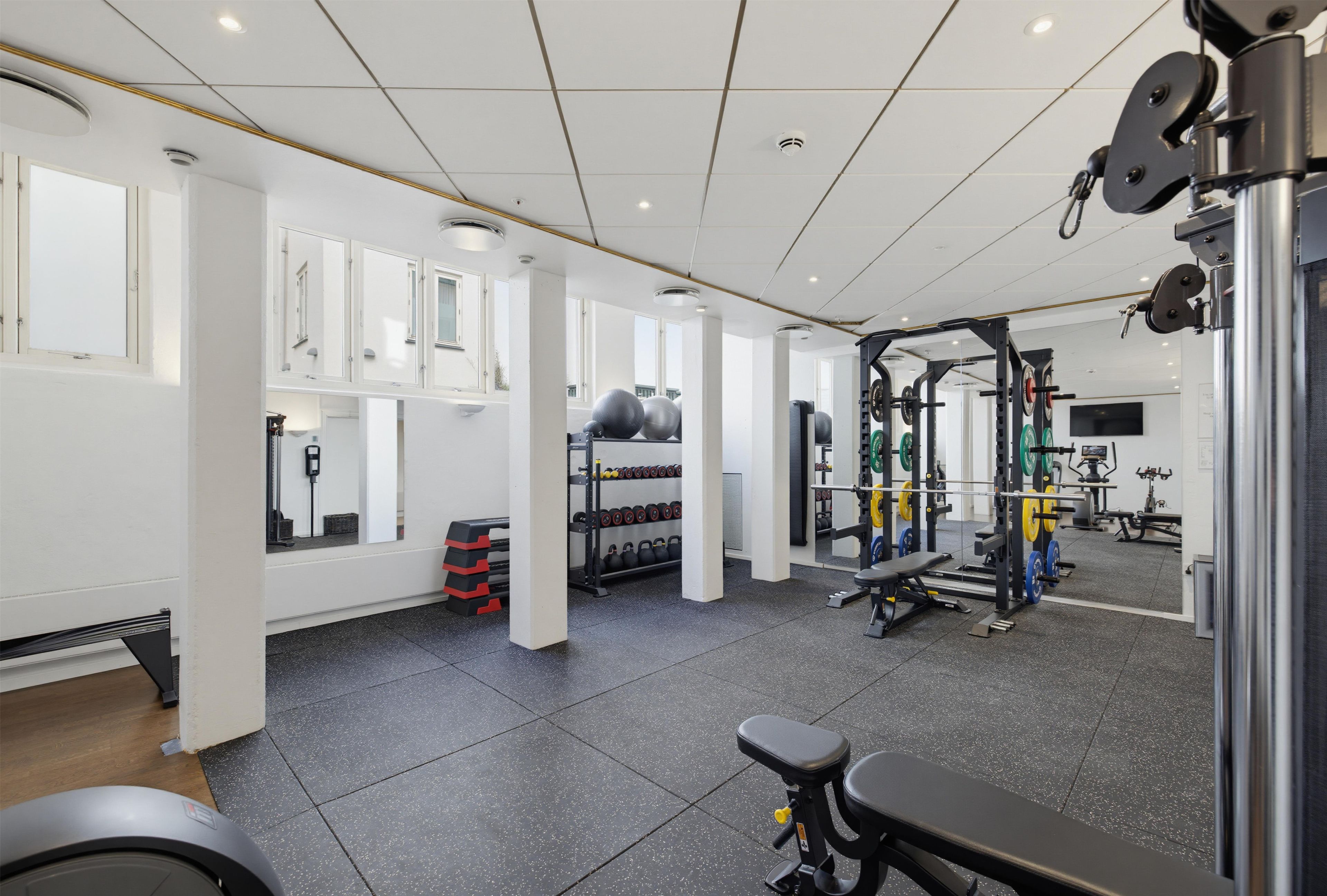 A gym with various exercise equipment, including weight racks and a bench.