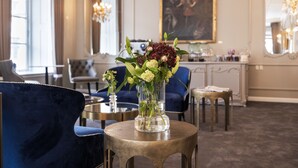 A room with a round table, a vase with flowers, a blue chair, and a painting on the wall. - Phoenix Copenhagen (Copenhagen)