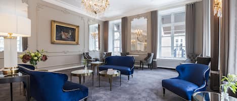 Una habitación espaciosa con un ventanal grande, un candelabro y un conjunto de sofá azul.