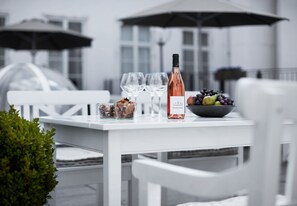 A white table with a bottle of wine, glasses, and a bowl of grapes. - Phoenix Copenhagen (Copenhagen)