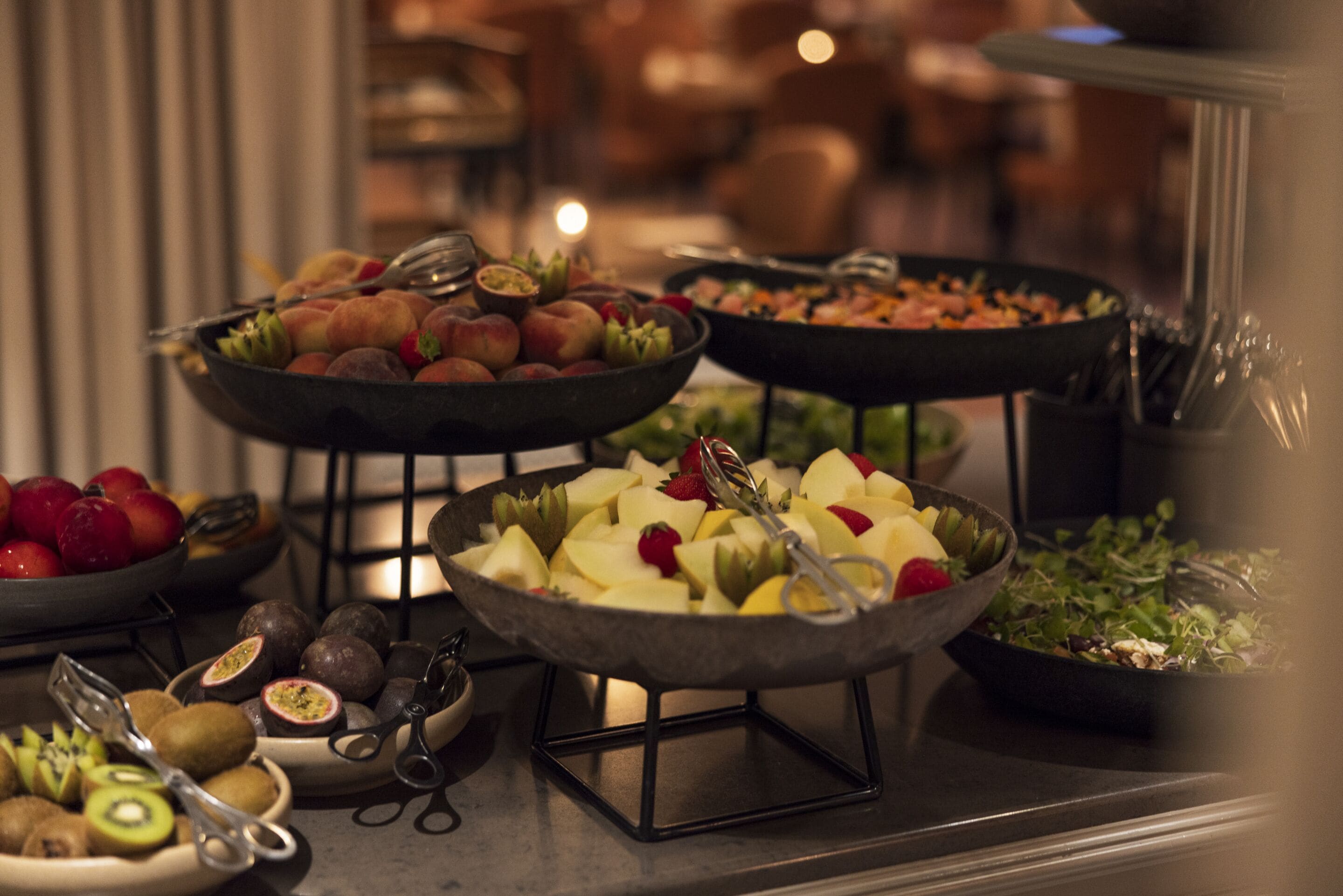Un buffet proposant une variété de fruits et de légumes, notamment des pommes, des kiwis et des fraises.