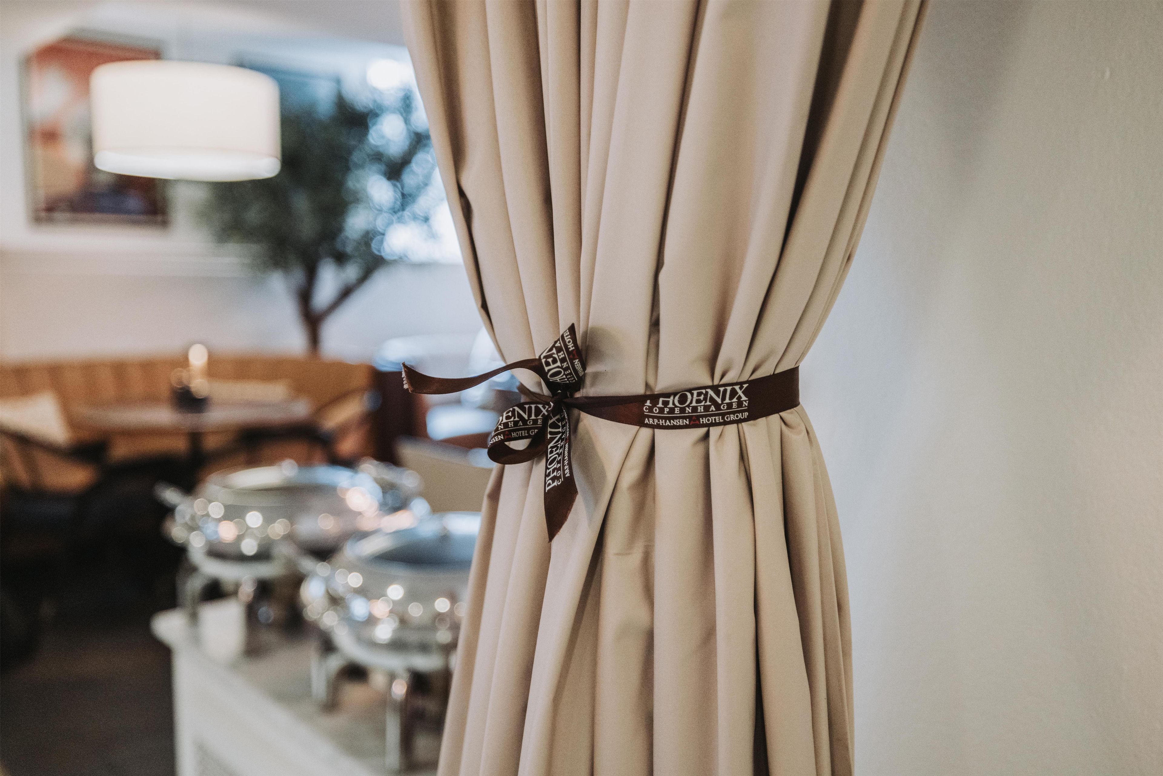 A curtain with a decorative ribbon and a hotel group logo.
