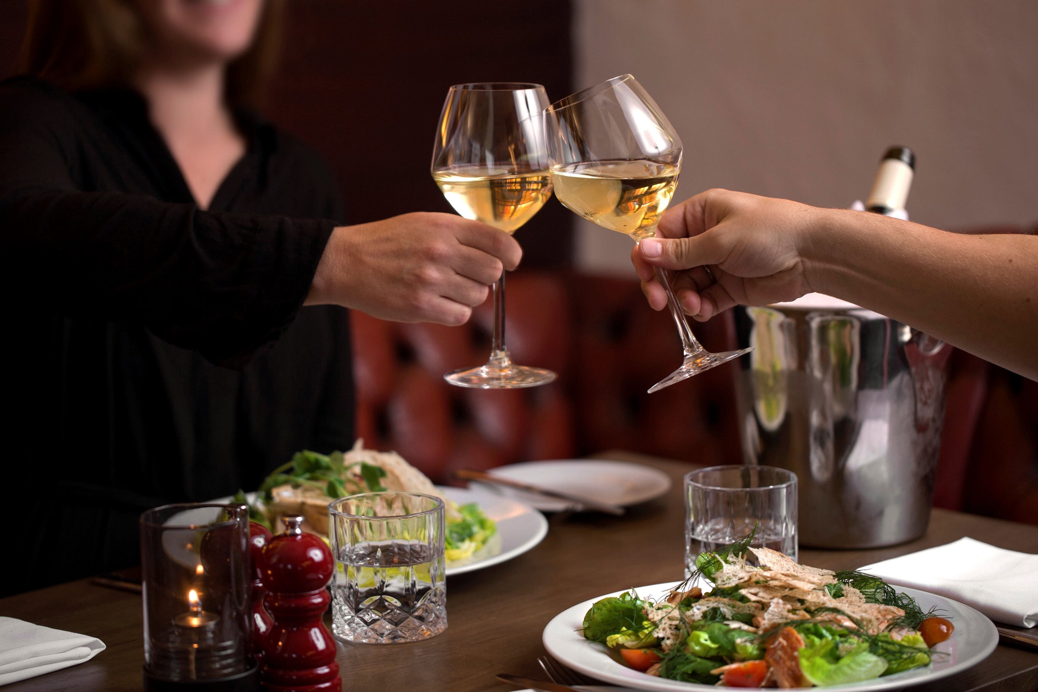 Une table à manger avec des assiettes remplies de nourriture, des verres et une bougie.