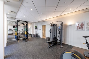 A gym with various exercise equipment, a treadmill, and informational posters on the walls. - Phoenix Copenhagen (Copenhagen)