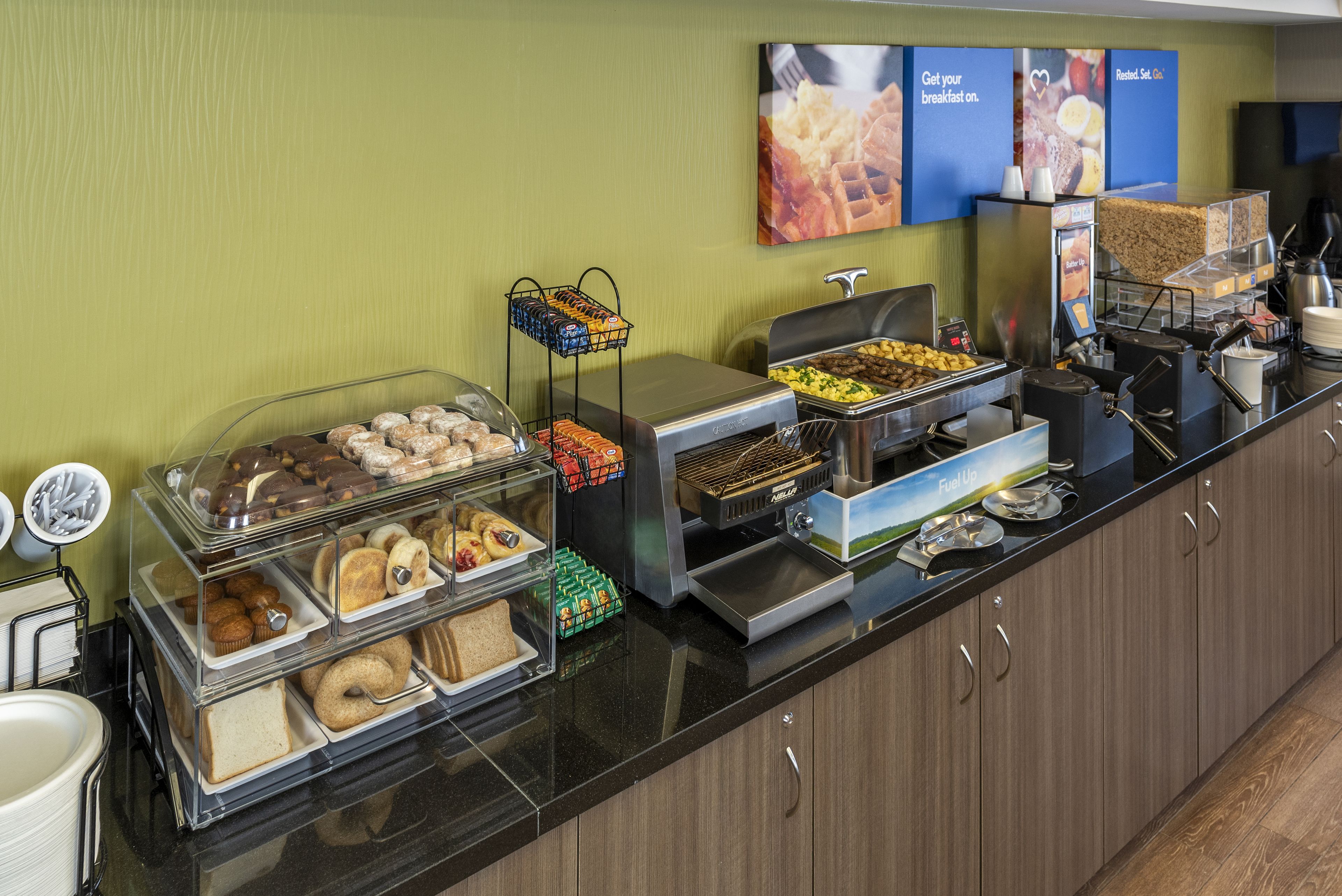 Un banco buffet con diversi cibi, tra cui pasticceria, panini e opzioni per la colazione.