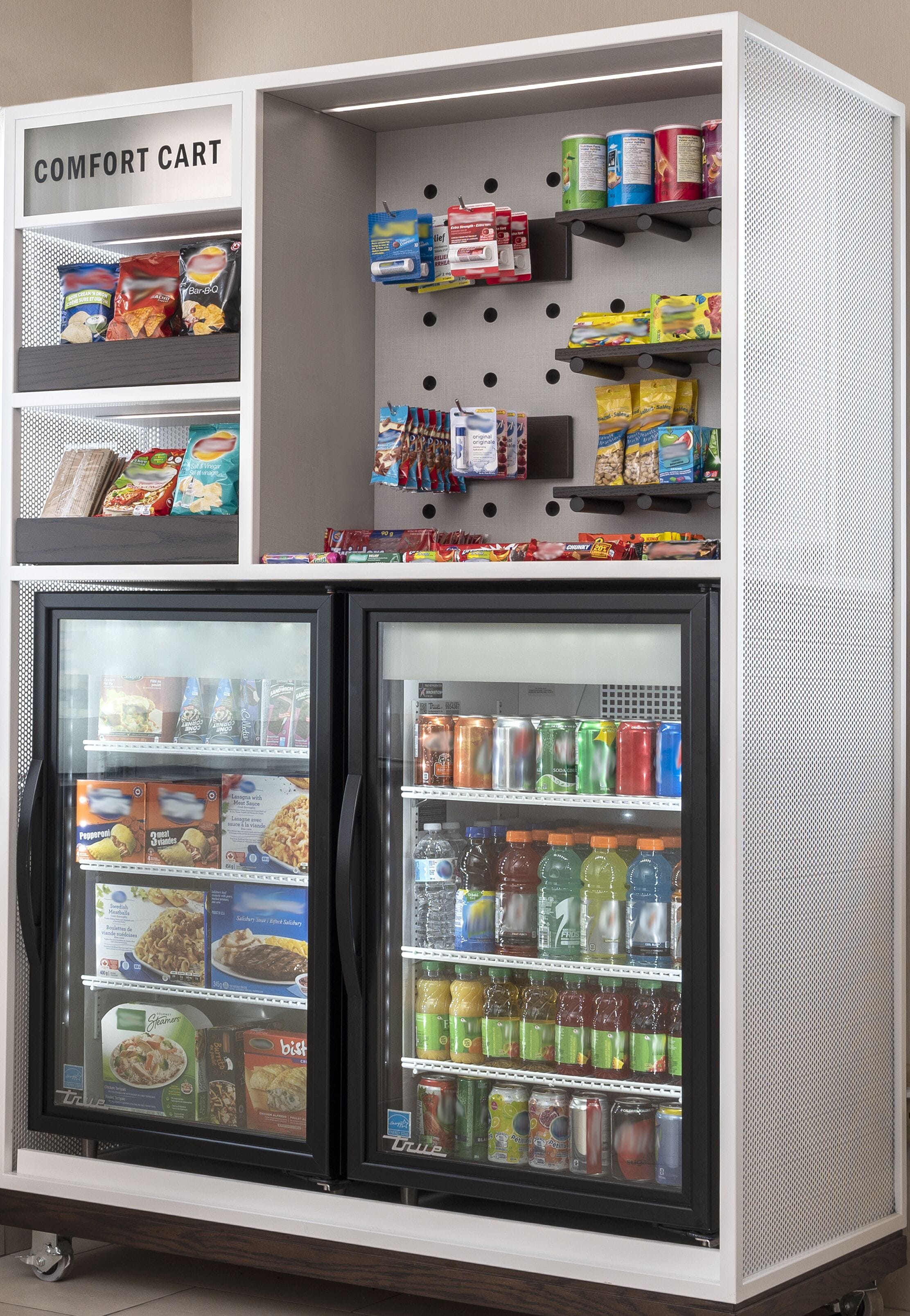 Máquina expendedora con un carrito de conveniencia encima, que contiene aperitivos y bebidas.