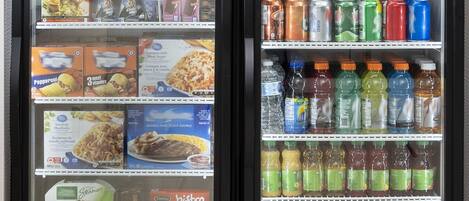 Un carrito de conveniencia con bocadillos, bebidas y un refrigerador lleno de comida y refrescos.