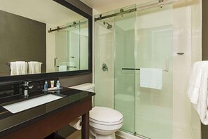 A modern bathroom with a glass-enclosed shower, a white toilet, and a black countertop with a sink.