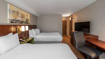 A hotel room with two beds, a desk with a chair, a television, and a painting on the wall.