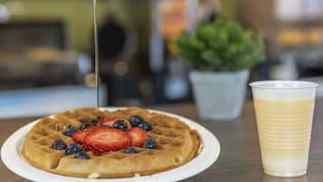 Una cialda con della frutta su un piatto e una tazza di caffè su un tavolo.