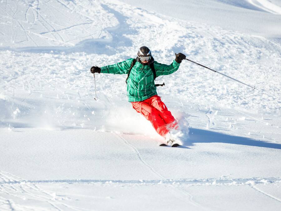 Une personne qui fait du ski sur une pente enneigée.