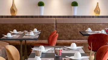 A restaurant with booths and tables, each set with white plates, cups, and cutlery.