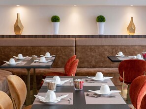 A restaurant with booths and tables, each set with white plates, cups, and cutlery. - Mercure Versailles Paris Ouest (Le Chesnay-Rocquencourt)