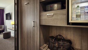 A hotel room with a minibar, a television, a lamp, a sofa, and a coffee table. - Mercure Versailles Paris Ouest (Le Chesnay-Rocquencourt)