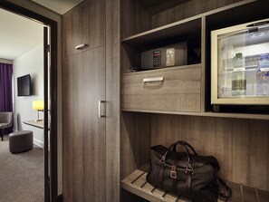 A hotel room with a minibar, a television, a lamp, a sofa, and a coffee table.