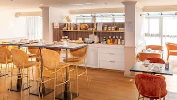 Un'area ristorazione moderna con buffet, posti a sedere al bar e vista sulla città.