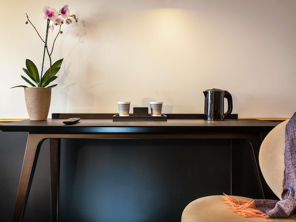 Een minimalistisch bureau met een potorkidee, twee koffiekopjes en een koffiepot.