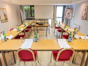 A conference room with multiple tables, chairs, and a projector screen. - Mercure Versailles Paris Ouest (Le Chesnay-Rocquencourt)