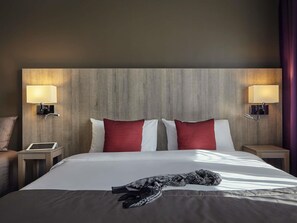 Une chambre d’hôtel avec un grand lit, deux tables de chevet avec des lampes, une tête de lit et une fenêtre avec des rideaux.