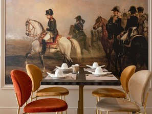 Una mesa de comedor con un cuadro de soldados a caballo, rodeada de sillas modernas.