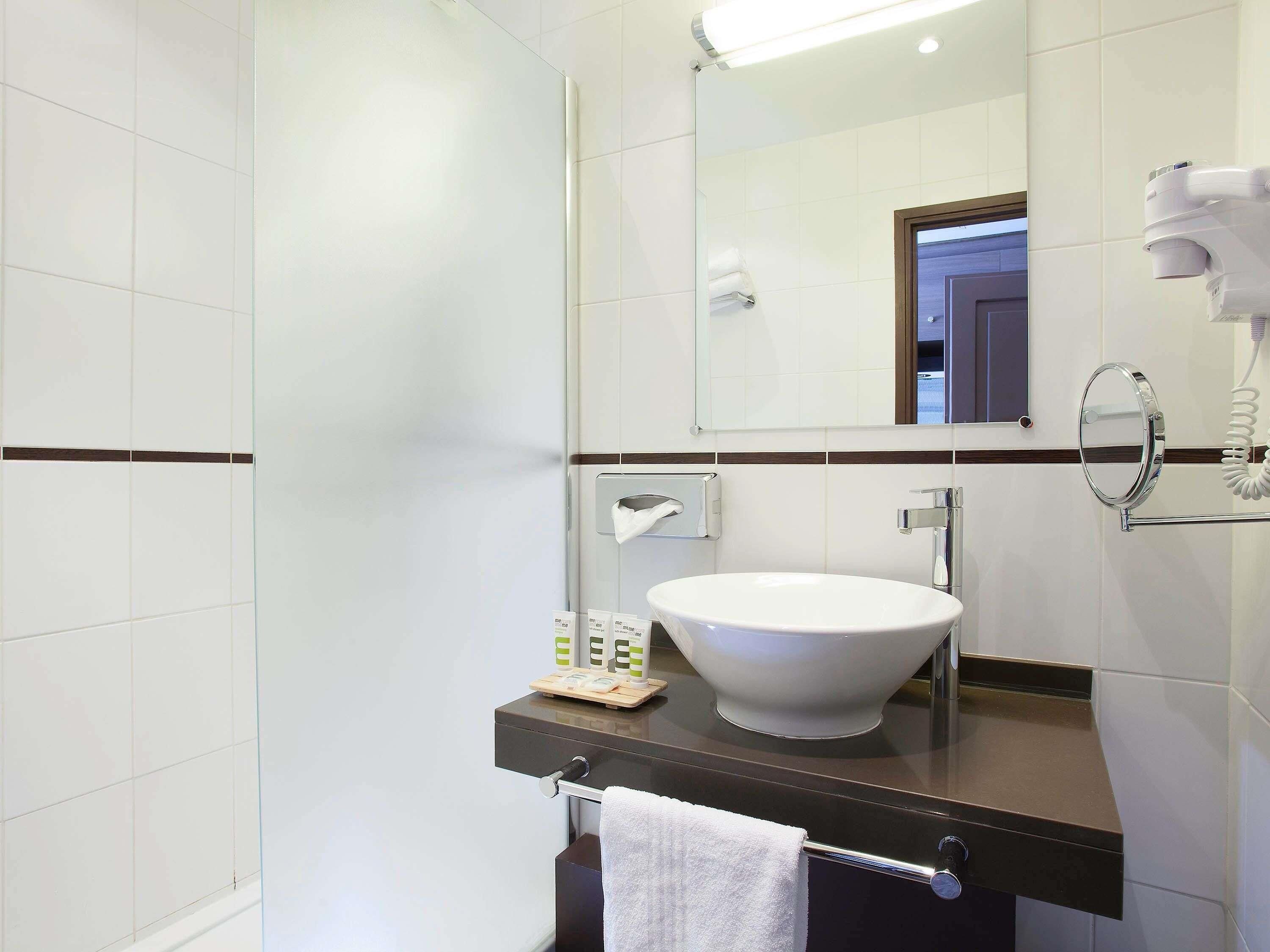 A modern bathroom with a white sink, a towel rack, a mirror, and a hairdryer.