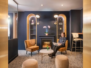 Uma sala de estar moderna com lareira, dois poltronas, uma mesa de centro redonda e uma estante de livros.