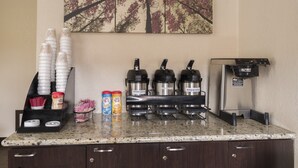 Estación de café con máquina de café, opciones de café descafeinado y normal, y dispensador de bebidas.
