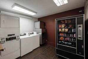 Una cocina compacta equipada con refrigerador, lavadora y máquina expendedora.