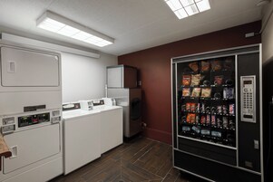 Una cocina compacta equipada con refrigerador, lavadora y máquina expendedora.
